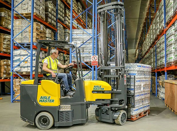 Worker driving an Aisle Master forklift  in a warehouse