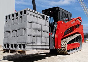 Manitou skid steer with tracks hauling cement blocks