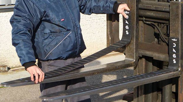 man putting magnetic fork pads onto onto a forklift