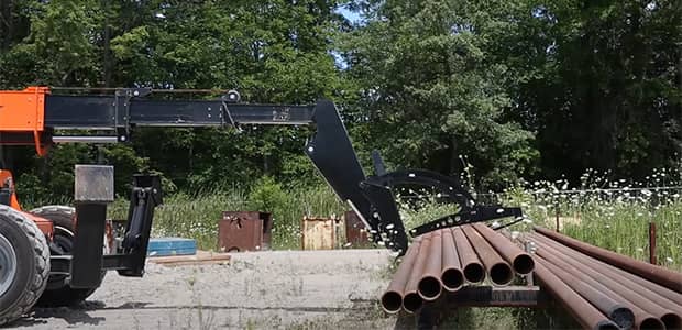 Equipment with a pipe grapple attachment moving pipes