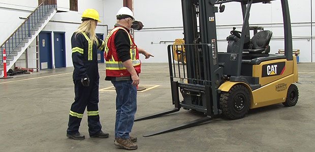 Two workers doing a forklift safety check with safety gear on