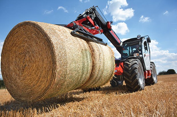 Manitou agricultural telehandler picking up a round bale