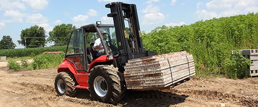 Manitou rough terrain agricultural forklift hauling lumber