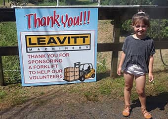 Girl standing beside a thank you poster for Leavitt's community commitment and sponsorship