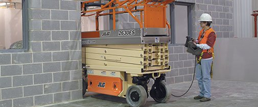 JLG industrial scissor lift being driven through a doorway