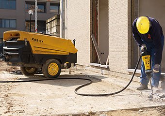 Worker using an Atlas Copco compressor