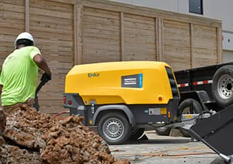 Worker using an Atlas Copco compressor