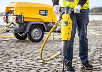 Worker using an Atlas Copco hand tool on a construction site