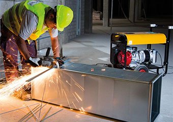 Worker using an Atlas Copco portable generator at a construction site