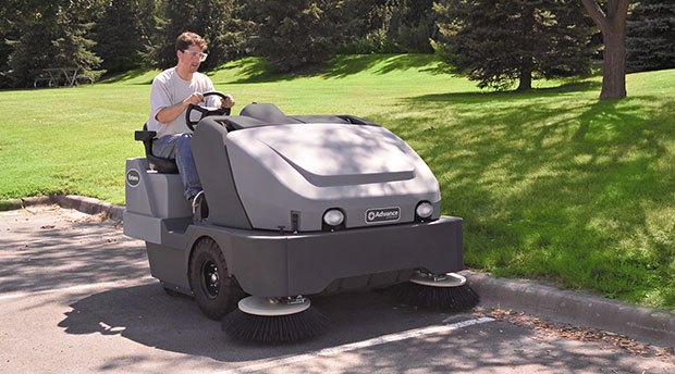 Worker using a new Nilfisk Advance sweeper to sweep a parking lot