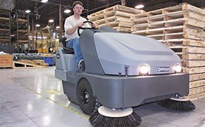 Worker using a Nilfisk Advance sweeper in a warehouse
