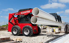 Manitou skid steers hauling pipes with a clamp