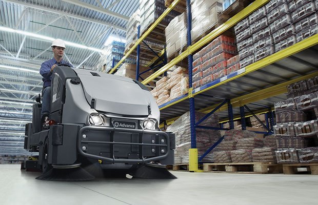 A sweeper scrubber cleaning a floor in a warehouse