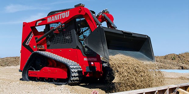 A Manitou track loader dumping dirt