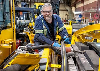 Service worker doing maintenance on a forklift engine