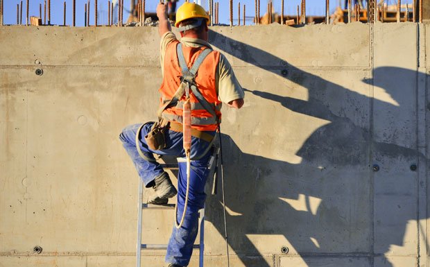 Construction worker practicing fall protection safety at a worksite